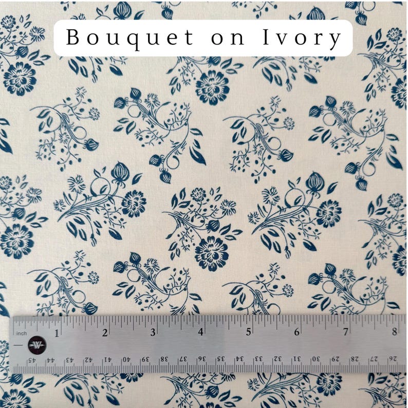May include: Ivory fabric with a repeating pattern of navy blue floral bouquets and foliage. The text "Bouquet on Ivory" is at the top. A ruler shows measurements up to 8 inches.