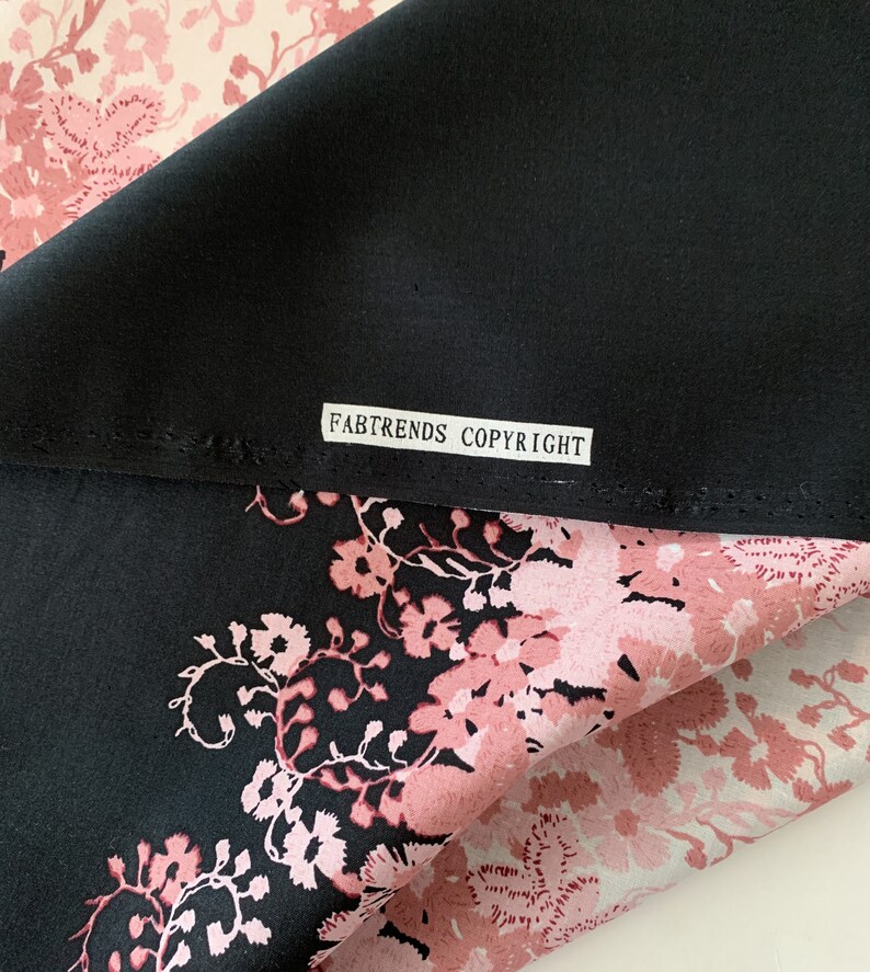 May include: Black fabric with a pink floral print. The fabric has a label that reads "FABTRENDS COPYRIGHT".