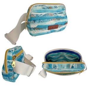 May include: A blue and white patterned fanny pack with a white adjustable strap and a gold zipper. The bag has a brown leather tag that says "Handmade".