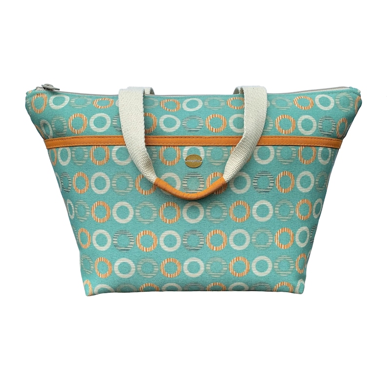 May include: A teal blue tote bag with orange and white circle pattern. The bag has two cream colored handles and a zipper closure.