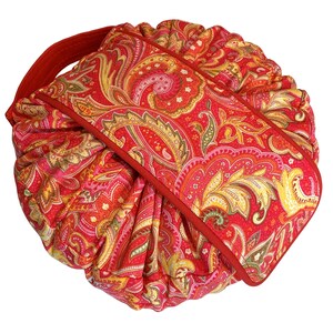 May include: Red paisley patterned drawstring bag with a red handle. The bag is folded and tied with a red ribbon.