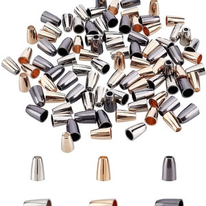 May include: A collection of metal cone-shaped beads in various metallic finishes, including gold, silver, and gunmetal. The beads are displayed in a scattered arrangement, with several individual beads shown below. These beads are likely used for jewelry making or crafting.