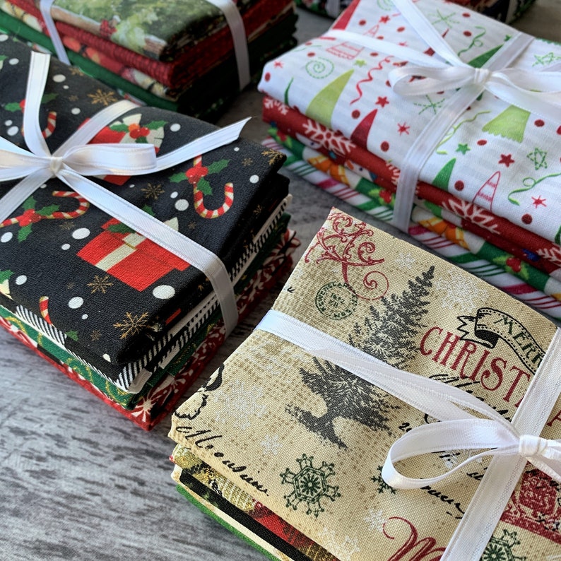 May include: A stack of Christmas fabric squares with various holiday patterns, including candy canes, snowflakes, and Christmas trees. The fabric is tied with white ribbon.