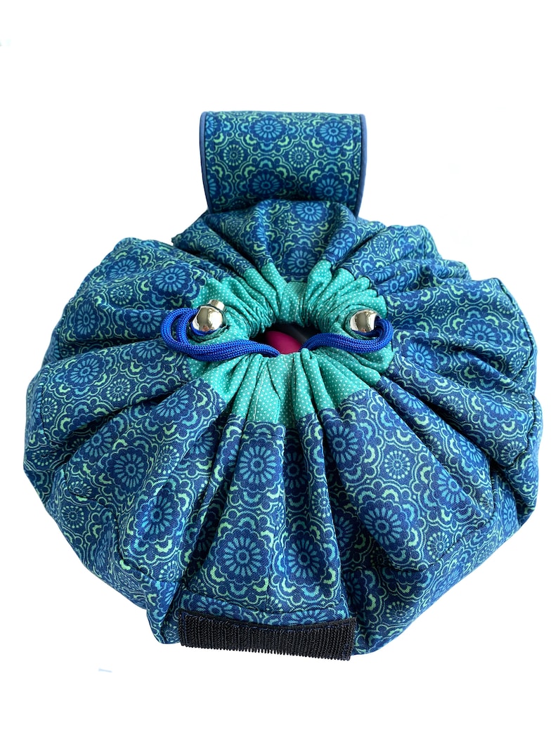 May include: A blue and green drawstring bag with a floral pattern. The bag has a handle and a zipper closure.