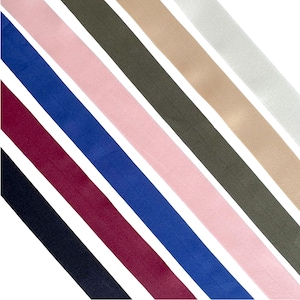 Può includere: Un assortimento di strisce di tessuto in vari colori, tra cui nero, bordeaux, blu, rosa, verde oliva, beige e bianco, disposte diagonalmente su uno sfondo bianco. Le strisce sembrano essere realizzate in un materiale liscio, possibilmente tessuto.