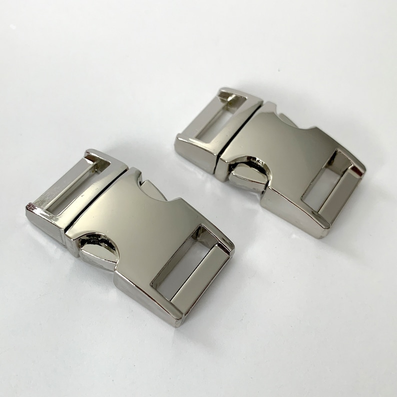 May include: Two silver metal side release buckles. The buckles are rectangular with a smooth, shiny finish.