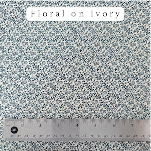 May include: Ivory fabric with a repeating pattern of small, dark teal floral designs. A metal ruler with inch measurements is at the bottom. The text "Floral on Ivory" is at the top.
