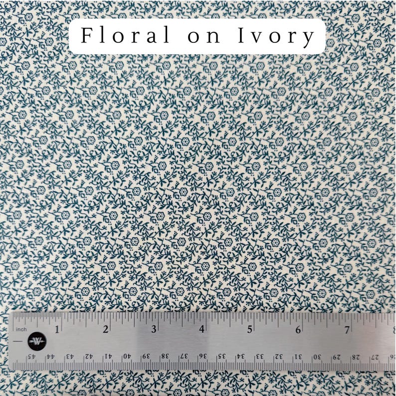 May include: Ivory fabric with a repeating pattern of small, dark teal floral designs. A metal ruler with inch measurements is at the bottom. The text "Floral on Ivory" is at the top.