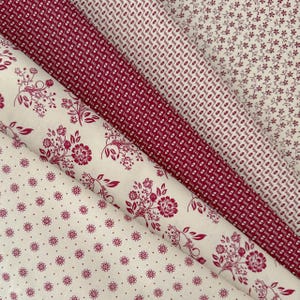 Op de afbeelding: Assortiment van stofstalen in rood- en cr&egrave;metinten. De stoffen tonen diverse patronen, zoals kleine bloemen, stippen en botanische motieven. De stoffen zijn diagonaal gerangschikt, wat de verschillende texturen en prints benadrukt. Ideaal voor knutselen.
