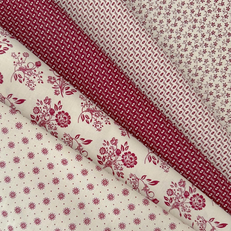 Op de afbeelding: Assortiment van stofstalen in rood- en cr&egrave;metinten. De stoffen tonen diverse patronen, zoals kleine bloemen, stippen en botanische motieven. De stoffen zijn diagonaal gerangschikt, wat de verschillende texturen en prints benadrukt. Ideaal voor knutselen.