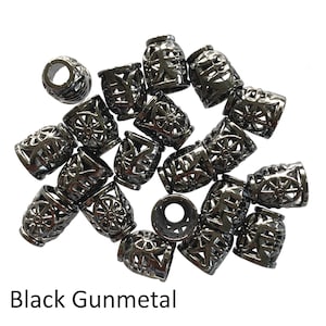 May include: A group of 18 black gunmetal metal beads with a decorative openwork design. The beads are arranged in a pile on a white background.