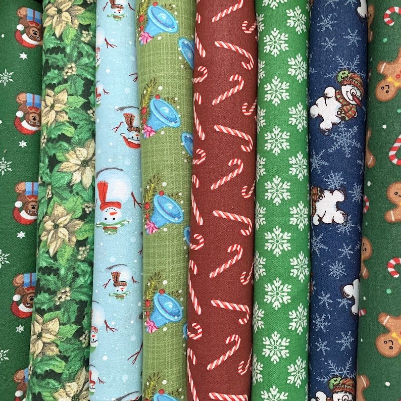 May include: A collection of eight different Christmas fabric scraps featuring various holiday themes, including snowmen, candy canes, bells, and snowflakes. The fabrics are in a variety of colors, including red, green, blue, and white.