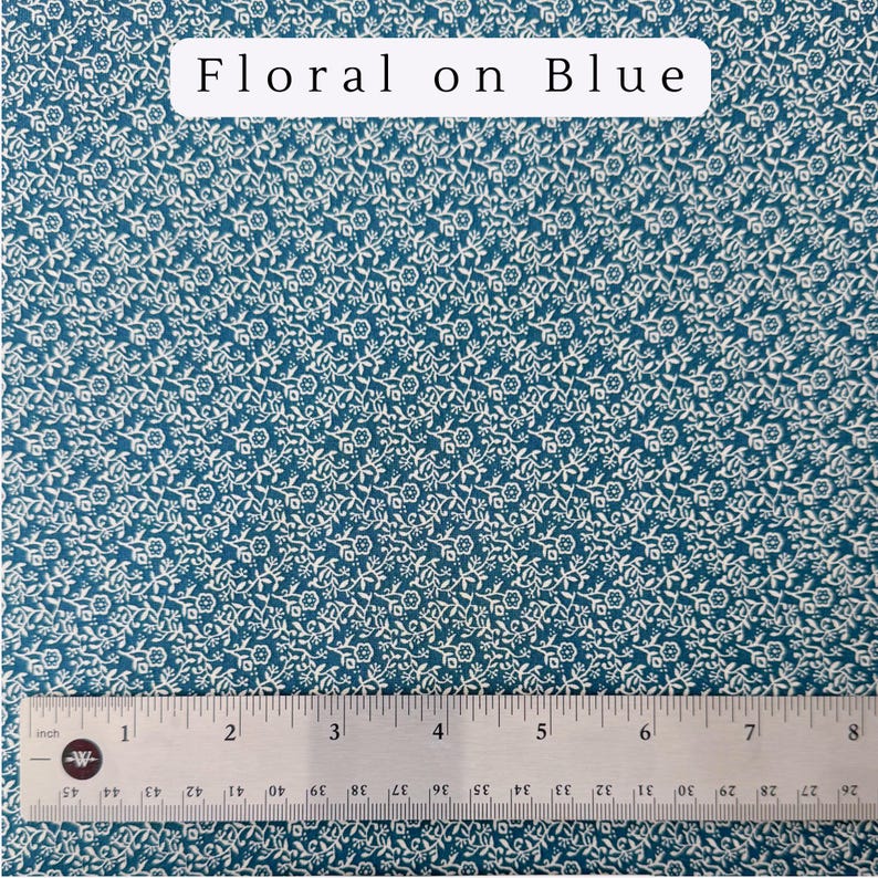May include: Teal fabric with a repeating white floral pattern. The text "Floral on Blue" is at the top. A ruler shows measurements in inches, with a total length of 8 inches.