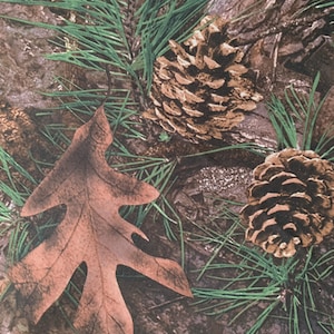 May include: A close-up of a camouflage fabric with brown pine cones and a brown leaf. The fabric has a woodland theme.