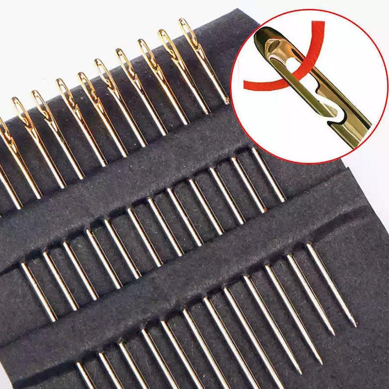 May include: A set of 20 gold-colored sewing needles in a black plastic case. The needles are arranged in rows and are all the same size. The case has a clear plastic lid.