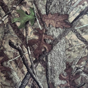 Pode incluir: Padrão de camuflagem com uma mistura de tons castanhos, bege e cinzentos, com uma folha verde e várias folhas castanhas. O design incorpora galhos de árvores e casca, criando um efeito de floresta realista.