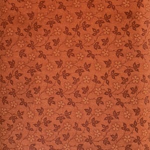 Puede incluir: Primer plano de una tela con un patrón floral repetitivo. El fondo es de color marrón anaranjado cálido. Viñas marrones oscuras con hojas y pequeñas flores se distribuyen uniformemente por la superficie.