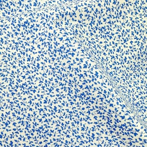 Könnte beinhalten: Ein Textilstoff mit einem dichten, sich wiederholenden Muster aus kleinen, leuchtend blauen, rankenartigen Zweigen mit winzigen Blättern und abgerundeten Knospen, die auf einem cremeweißen Hintergrund gedruckt sind und ein durchgehendes botanisches Design bilden.