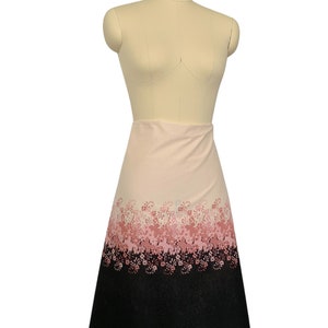 May include: A pink and black A-line skirt with a floral print. The skirt has a gradient pattern with pink flowers on a white background that fades to black at the bottom.