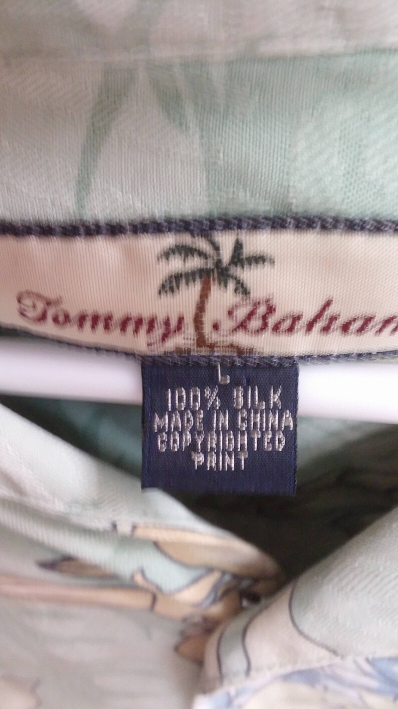 May include: A light green silk shirt with a palm tree print and the text "Tommy Bahama" on the label. The label also states "100% Silk, Made in China, Copyrighted Print".