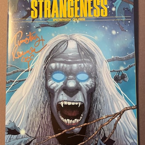 May include: Comic book cover for "High Strangeness" featuring a monstrous creature with glowing blue eyes and an open mouth. The title is in yellow, with author names above. The book is labeled "Book Two: 1975".