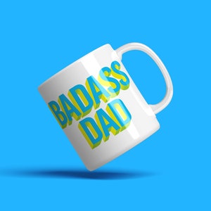May include: White ceramic mug with a blue and yellow 3D design that says "BADASS DAD".