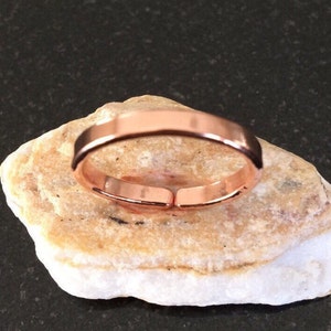 May include: A simple copper ring with a smooth, polished finish. The ring is open ended and adjustable.