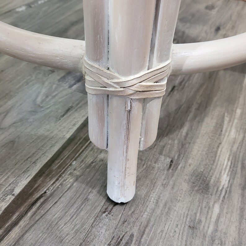 May include: White painted wooden stool with a woven rattan base and a round top. The stool has a distressed white paint finish and a simple design.