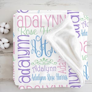 May include: A white fleece blanket featuring a repeating pattern of the name Adalynn in pink, purple, and blue, along with the full name Adalynn Rose Harris and a blue monogrammed letter A, with a soft white interior lining and folded corner.