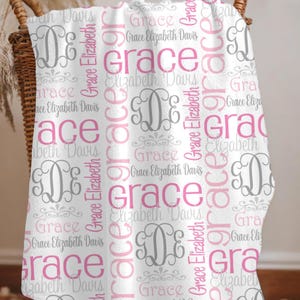 May include: A white fleece blanket featuring a repeating pattern of the name Grace Elizabeth Davis in various pink and gray fonts. The design includes large pink text, smaller gray script, and decorative gray monogrammed initials GDE.