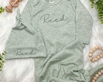 May include: A green and white baby gown and matching hat with the name "Reed" embroidered on both pieces.