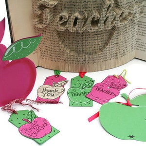 May include: Five apple-shaped gift tags with green leaves and red and green polka dots. The tags have different messages, including "Thank You", "Teacher", and "Best Teacher".