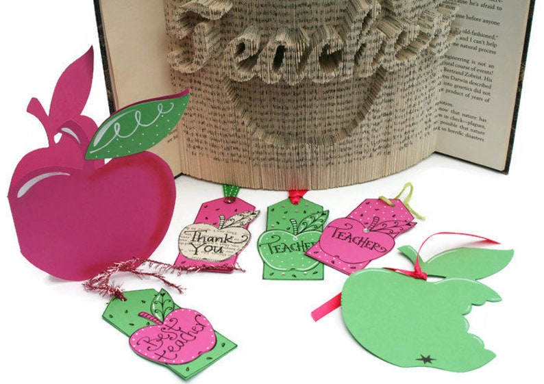 May include: Five apple-shaped gift tags with green leaves and red and green polka dots. The tags have different messages, including "Thank You", "Teacher", and "Best Teacher".