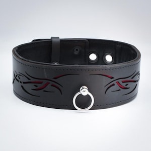May include: Black leather collar with a red and black tribal design and a silver ring.