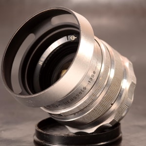 May include: A white ceramic mug with a black handle and the text "But First, Coffee" in a black, handwritten-style font. The mug is on a white surface.