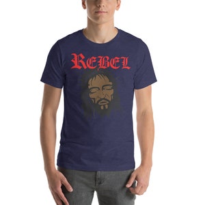 May include: A navy blue t-shirt with the word "REBEL" in red lettering and a black and brown image of a man's face with his eyes closed. The man's face is surrounded by a crown of thorns.