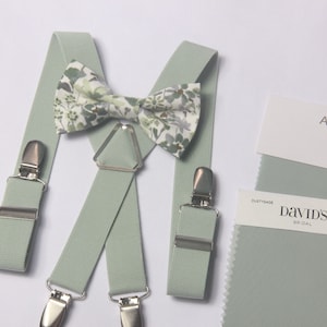 Könnte beinhalten: Salbeigrüne Hosenträger mit silbernen Clips und einer passenden Fliege mit Blumenmuster. Der Stoffmuster ist mit "A Z A Z Chiffon/Mesh/Linen Agave" und "David's Bridal Dusty Sage Chiffon" beschriftet.