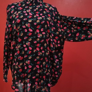 May include: A black long-sleeved shirt with a floral print featuring pink, red, and brown roses. The shirt has a button-up collar and a relaxed fit.