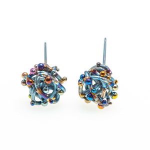 May include: A pair of blue titanium earrings with a cluster of colorful beads. The earrings are made of a twisted wire design and have a post back.