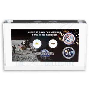 Può includere: Un'immagine in bianco e nero di un display incorniciato che presenta un pezzo di foglio di Kapton CM di Apollo 15 e una roccia lunare NWA 10203. Il display include anche una foto del modulo lunare Apollo 15 sulla luna, una foto dell'equipaggio dell'Apollo 15 e la patch della missione Apollo 15.