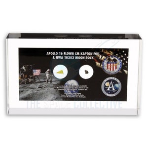 Può includere: Una teca in acrilico trasparente con un bordo nero, che mostra un pezzo di roccia lunare e un pezzo di foglio di Kapton che ha volato durante la missione Apollo 16. La teca include una foto dell'equipaggio dell'Apollo 16 sulla luna, la patch della missione e il logo della NASA. Il testo "APOLLO 16 FLOWN CM KAPTON FOIL & NWA 10203 MOON ROCK" è stampato sulla teca.