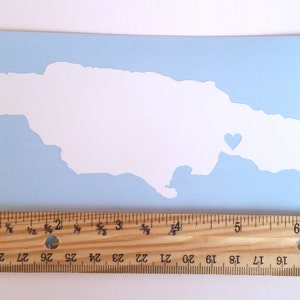 May include: A white vinyl decal of the outline of Jamaica with a small heart in the eastern part of the island. The decal is on a light blue background.