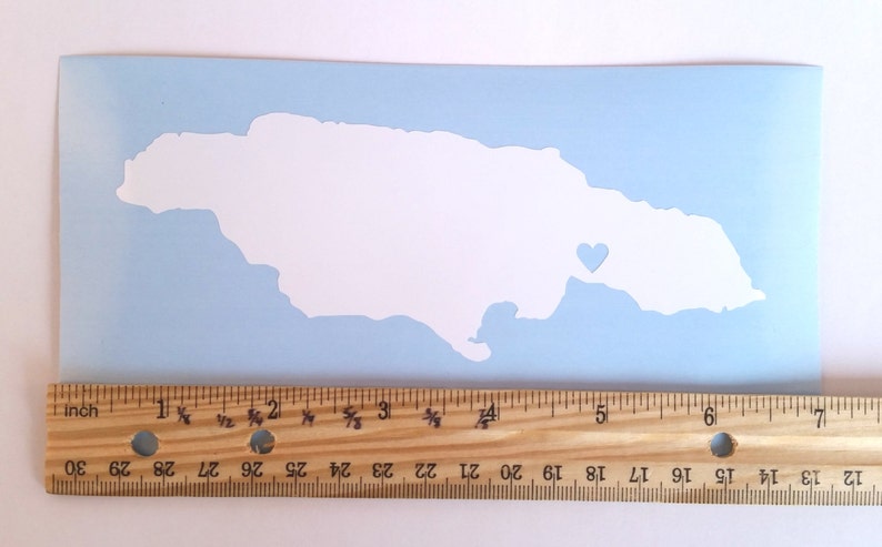 May include: A white vinyl decal of the outline of Jamaica with a small heart in the eastern part of the island. The decal is on a light blue background.
