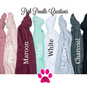 Puede incluir: Una selecci&oacute;n de camisetas de varios colores, incluyendo malva, melocot&oacute;n, granate, menta, blanco, gris claro, carb&oacute;n y negro. Las camisetas est&aacute;n dobladas y dispuestas en fila. Pink Poodle Creations est&aacute; escrito en la parte superior de la imagen.