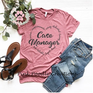 May include: A pink t-shirt with a black circle design that says "Case Manager" with the words "compassionate, caring, dedicated, loving, warm, fun, reliable, loyal, kind" around the circle. The shirt is laid out on a white surface with a pair of brown sandals and blue jeans.