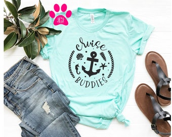 May include: A light blue t-shirt with a black anchor and the text "Cruise Buddies" in a circle with seashells, a starfish, and a seahorse.