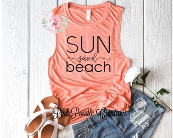 May include: A coral-coloured sleeveless tank top with the text "SUN sand beach" printed in black.