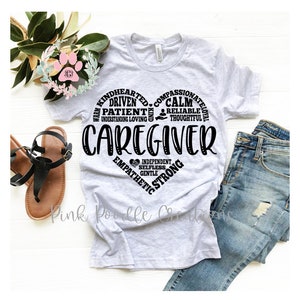 May include: A gray t-shirt with a black heart design. The heart is filled with words describing the qualities of a caregiver, including warm, kindhearted, compassionate, driven, patient, understanding, loving, calm, reliable, thoughtful, independent, selfless, gentle, and strong.