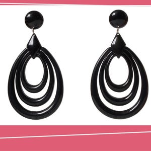 May include: A pair of black, retro-style earrings. Each earring features a circular stud, a diamond-shaped connector, and three nested teardrop-shaped loops. The earrings are made of a glossy, dark material.