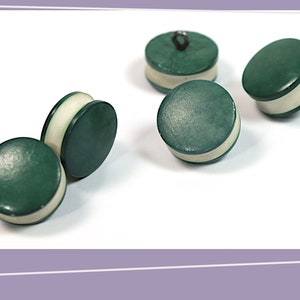 May include: Five green and white buttons with a white rim. The buttons are round and have a smooth surface.